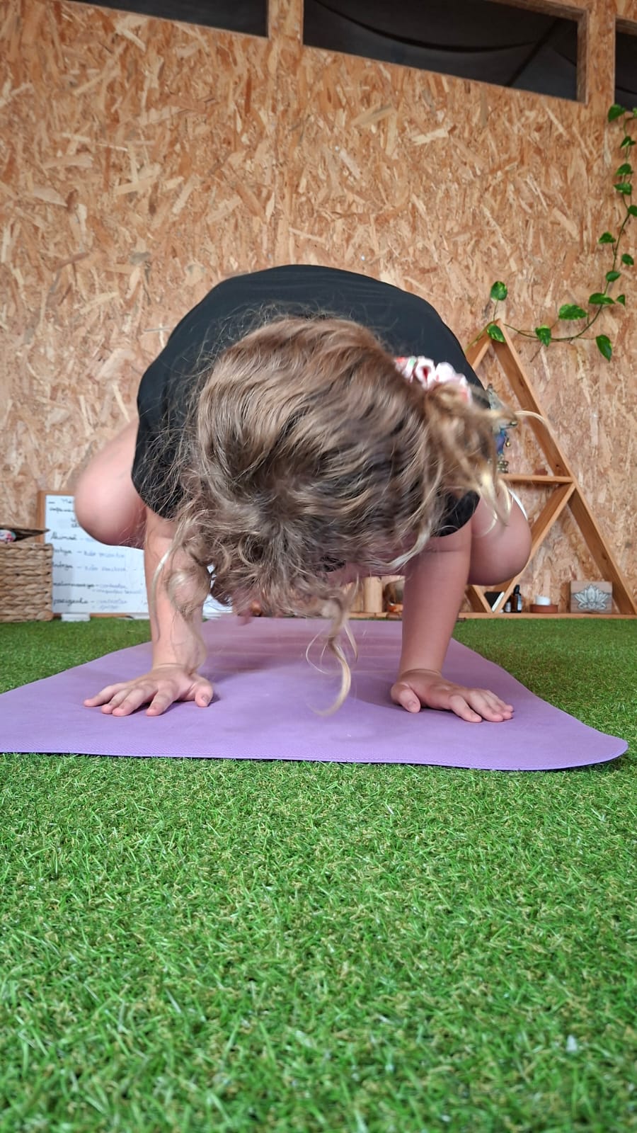 Criança a praticar uma postura de yoga num tapete ao ar livre